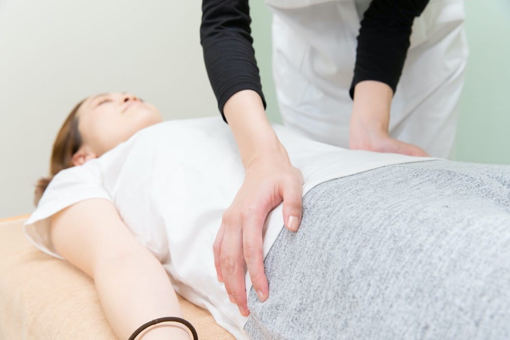 Pacjent podczas sesji terapeutycznej na stole — rehabilitacja kości ogonowej