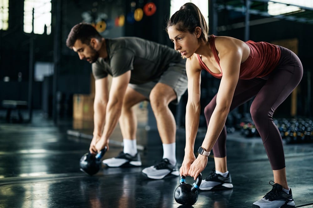 Osoby ćwiczące z kettlebell na siłowni — trening siłowy w dojrzałym wieku
